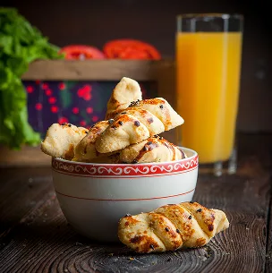 Fresh baked savory croissants served in a bowl with orange juice on a wooden table